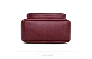Detailed bottom view of burgundy leather shoulder bag with fine stitching and rounded edges