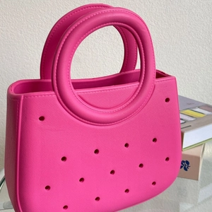 Sac de plage rose fuchsia en EVA avec design perforé et anses rondes vue de côté