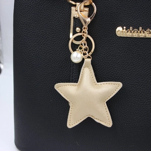 Black pebbled leather handbag featuring a yellow star pendant and white pearl detail