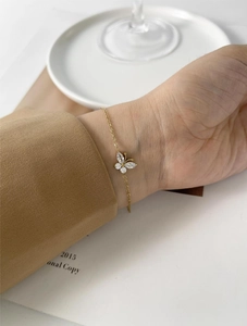 Detail of 18K gold butterfly bracelet featuring marquise zirconia on a woman's wrist