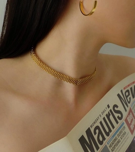 Elegante collana girocollo a catena multistrato dorata indossata da una modella con luce morbida