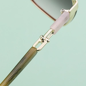 Macro detail of elegant gold jewelry-style hinge and multi-color temples on sunglasses