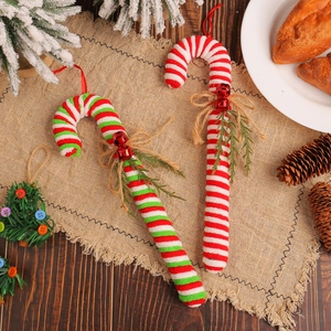 Festive red and white candy cane Christmas tree hanging ornaments with bells on wood surface