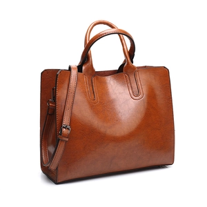 Detail of brown leather tote bag with glossy finish and adjustable shoulder strap
