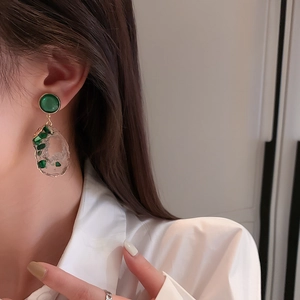 Detailed view of irregular emerald green earrings with gold plating and clear stone resin