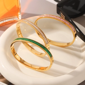 Classic gold titanium steel bracelets with colorful zircon stones on a white ceramic plate