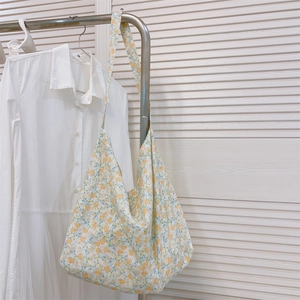 Floral cotton tote bag with vintage rabbit print hanging on a metal rack in a bright room