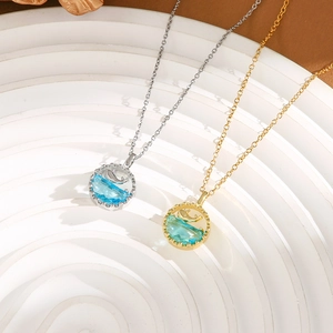 Detailed macro view of whale and wave pendants in gold and silver with blue crystal