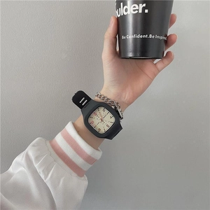 Close-up of square black watch with white dial paired with a metallic chain bracelet