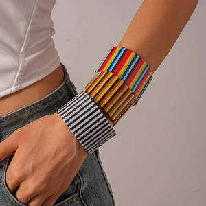 Stacked wide acrylic cuff bracelets featuring vertical stripes in multiple colors