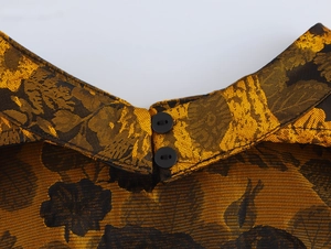 Detailed close-up of high-neck vintage jacquard fabric with golden patterns and black buttons