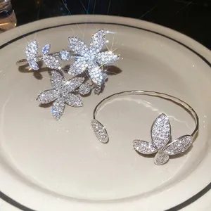 Sparkling silver flower and butterfly open bangles with zircon inlay in ceramic dish