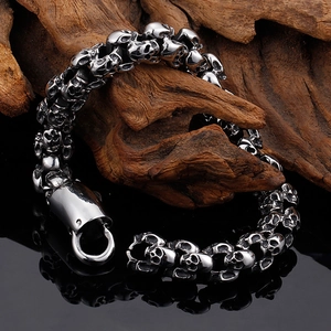 Macro shot of silver skull link bracelet on weathered wood over black reflective background