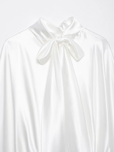 Dettaglio del tessuto in raso bianco e dell'elegante fiocco sullo scollo della camicetta