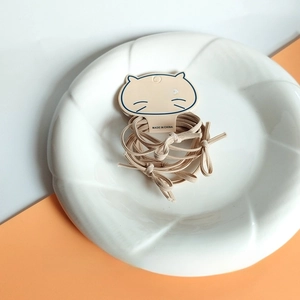 Close-up of beige high-elasticity hair ties on a ceramic plate for women hair styling