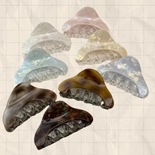 Detail view of various retro acrylic hair claw clips in marble and tortoiseshell patterns