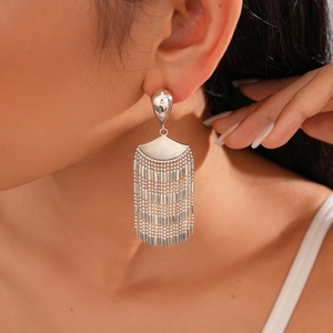 Close-up of silver long fringe tassel earrings on ear featuring metallic chain layers