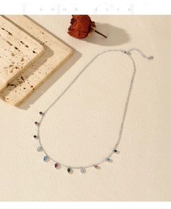 Detail of S925 silver necklace with multi-colored teardrop gems on a stone background