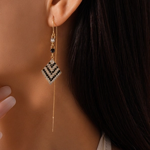 Detail of long geometric rhombus earrings with black stones and sparkling rhinestones