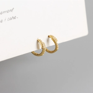 Macro detail of S925 silver huggie earrings with gold plating and paved cubic zirconia