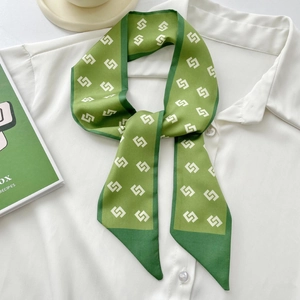 Elegant green floral silk scarf headpiece draped on a white shirt with book background