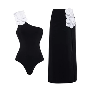 One-shoulder black one-piece swimsuit with 3D white floral applique and matching skirt