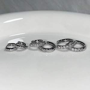 Three sizes of silver pavé hoop earrings with white crystals on a white ceramic tray