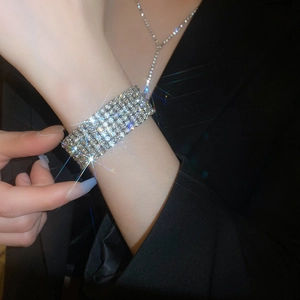 Vue rapprochée du bracelet à strass multi-rangs argenté porté sur une veste noire