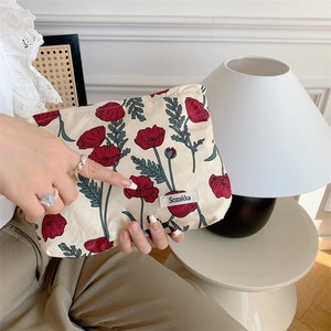 Detailed view of floral makeup bag with red poppy print and Sozakka brand tag