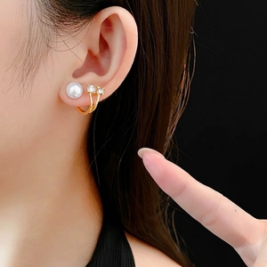 U-shaped gold pearl earrings with sparkling rhinestones shown on a model's ear