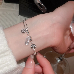 Detail shot of silver bracelet with abacus and coin charms worn with luxury accessories