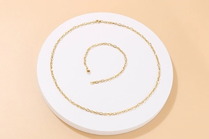 Minimalist gold O-chain necklace and bracelet set displayed on a circular white platform