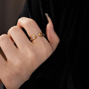 Close-up of golden teardrop zircon open ring worn by model on a dark background
