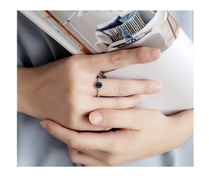 Close-up of S925 silver ring with a round blue sapphire stone on a hand with a magazine