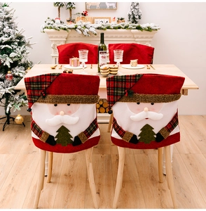 Detail of Santa Claus chair covers with red velvet and green plaid hat in a festive dining room
