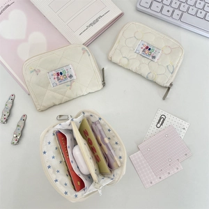 Detailed interior view of quilted cream wallet showing three compartments for cards and earbuds