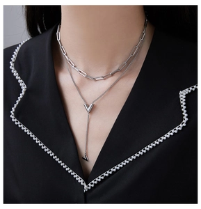Detail of silver layered V-shape pendant necklace on model with black blazer