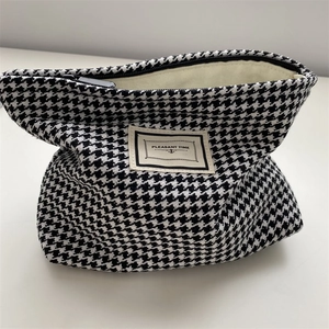 Detail of houndstooth toiletry bag with zipper closure and Pleasant Time label