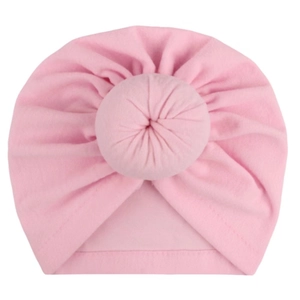 Detail view of pink cotton baby turban hat with soft donut knot decoration on white background