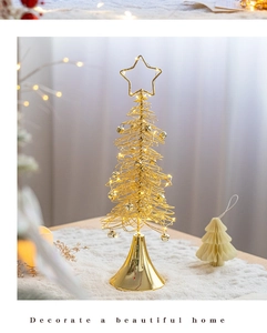 Close-up of lighted golden wire Christmas tree ornament with star topper on white faux fur