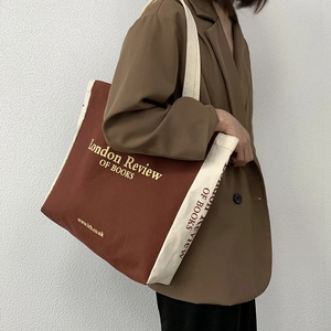Dettaglio della grande borsa tote in tela marrone con stampa London Review of Books su modella