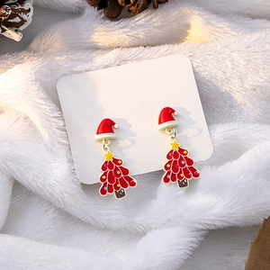 Close-up of Christmas tree stud earrings with a red Santa hat on soft white fur backdrop