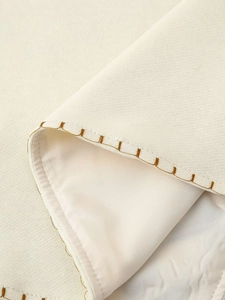 Close-up of beige vintage vest showing textured fabric and brown contrast stitching