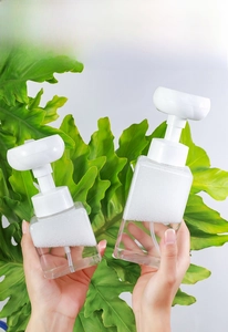Macro view of flower-shaped foam pump on transparent square facial cleanser dispenser bottle