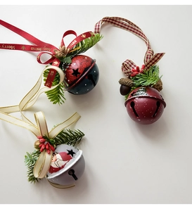 Flat lay of Christmas iron bells with pine needles, red berries and Merry Christmas ribbons