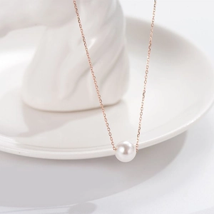 Elegant rose gold chain necklace with a single white pearl pendant on a white tray