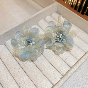 Close-up of handmade lace flower earrings with blue and yellow fabric petals and pearls