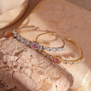 Elegant two-piece gold and silver oval zircon open bracelets on natural stone display
