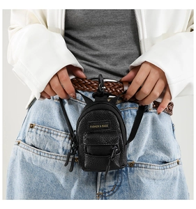 Close-up of mini black lychee leather bag charm attached to a denim waistband for kids