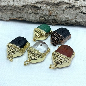 Macro shot of five colored glass Buddha head pendants with gold metal edge detailing